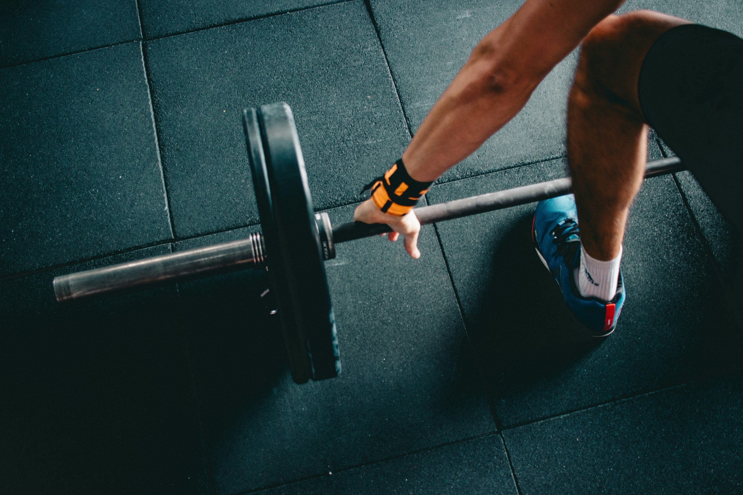 Sporter pakt een barbell vast tijdens krachttraining met een personal trainer